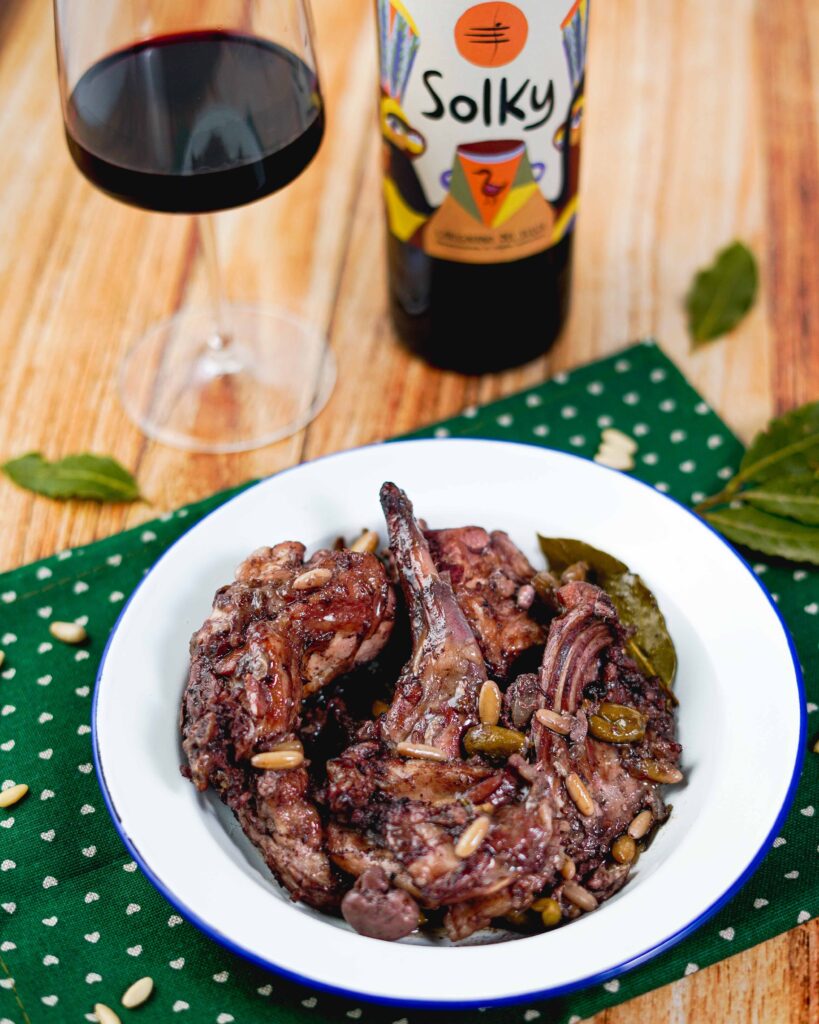 coniglio nel piatto con bicchiere di vino e bottiglia sul tavolo