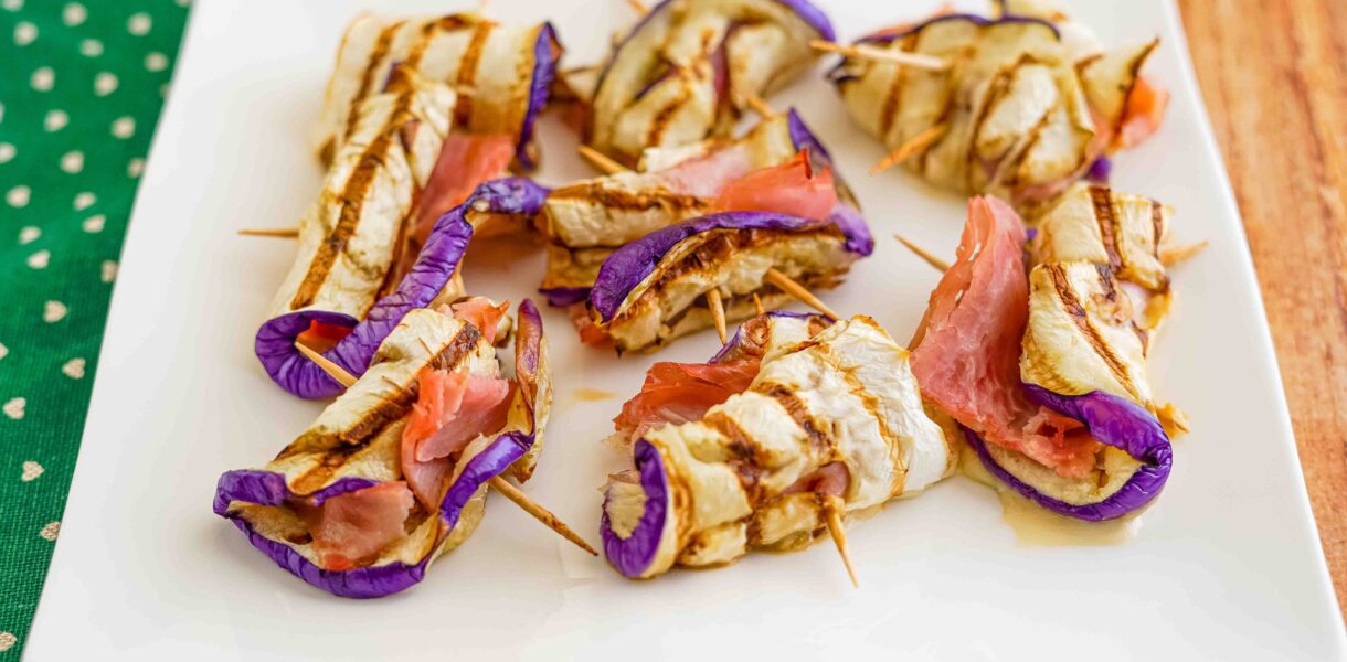 piatto di involtini nello stecchino di melanzane e prosciutto su piatto bianco