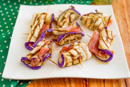 piatto di involtini nello stecchino di melanzane e prosciutto su piatto bianco