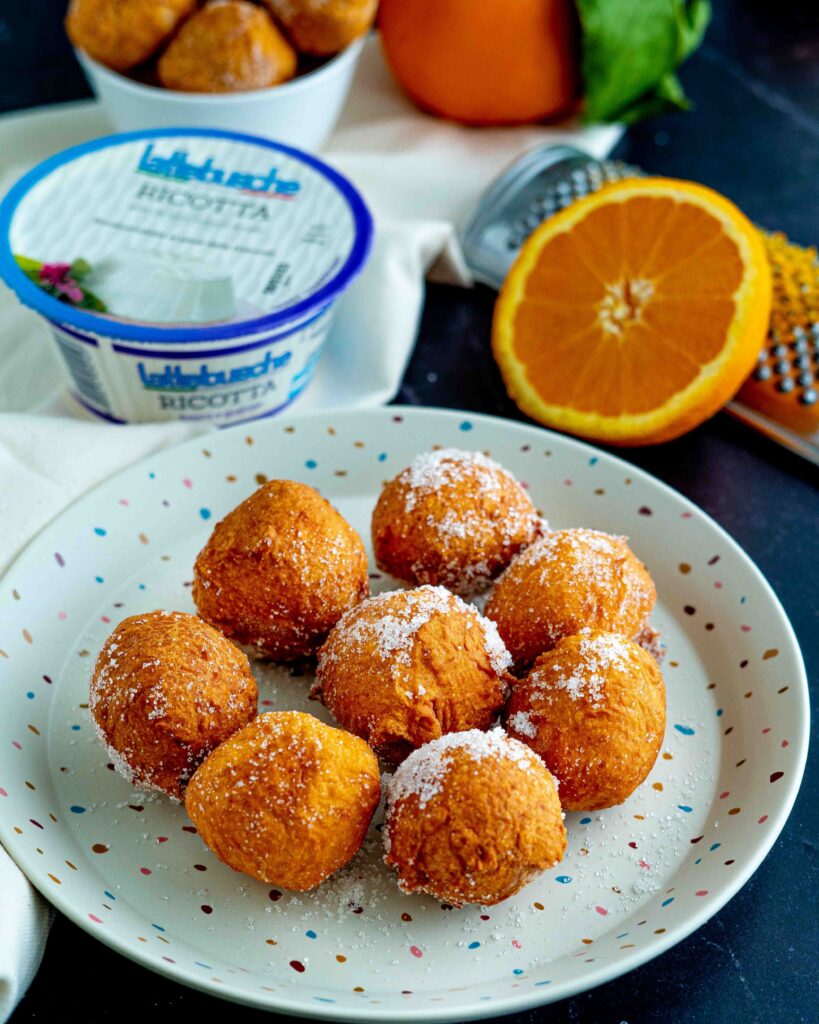 brugnoli sul piatto colorato con grattugia e arancia sul tavolo e ciottola con brugnoli con confezione di ricotta