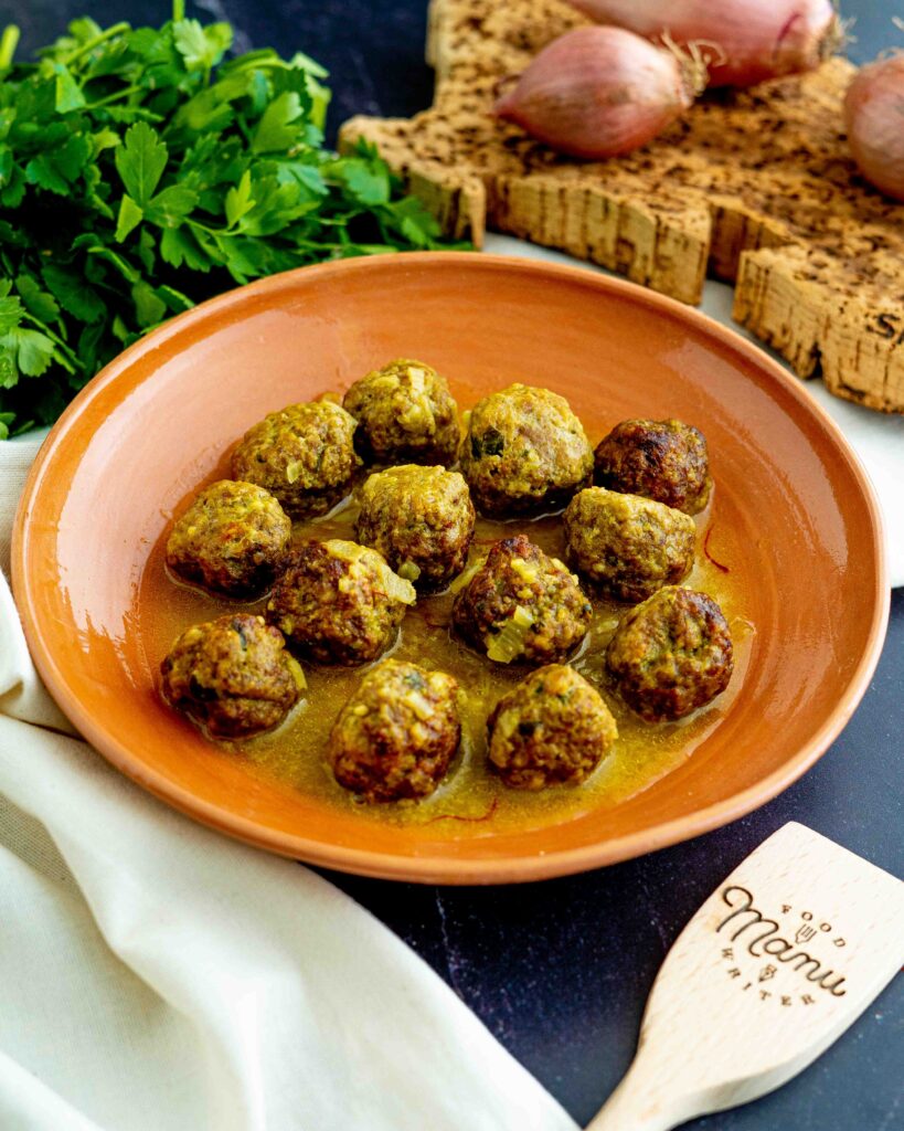 polpette allo zafferano dentro piatto cn mestolo e zafferano e cipolla con strofinaccio