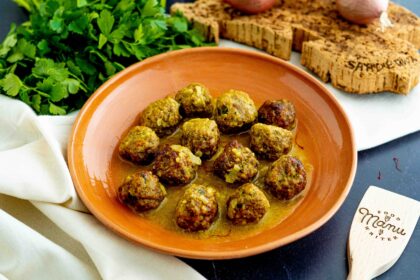 polpette allo zafferano in piatto con prezzemolo cipolle e mestoli