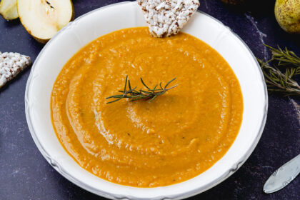 contenitore di ceci con piatto di vellultata sopra rosmarino e pere aperte sul tavolo con cipolle