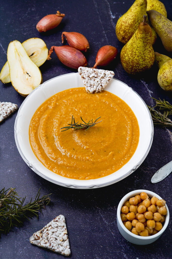 piatto con vellutata cucchiaio e contenitore di ceci con pere e cipolle sul tavolo