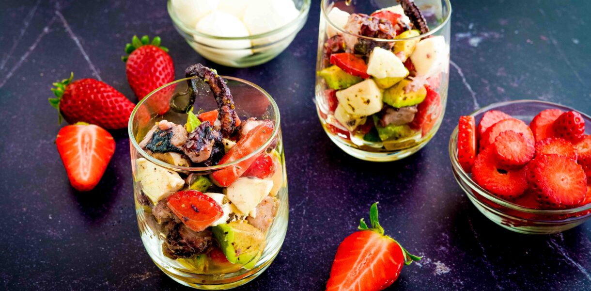 due bicchieri sul tavolo con fragole. dentro il bicchiere avocado polpo fragole e mozzarelline
