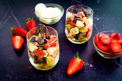 due bicchieri sul tavolo con fragole. dentro il bicchiere avocado polpo fragole e mozzarelline