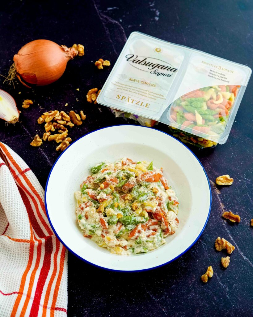 Pasta tipica del trentino alto adige con ricotta e noci, sul tavolo nero noci e cipolla 