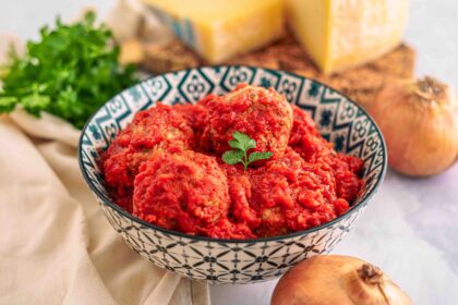 polpette in ciottola con formaggio e cipolle con prezzemolo sul tavolo