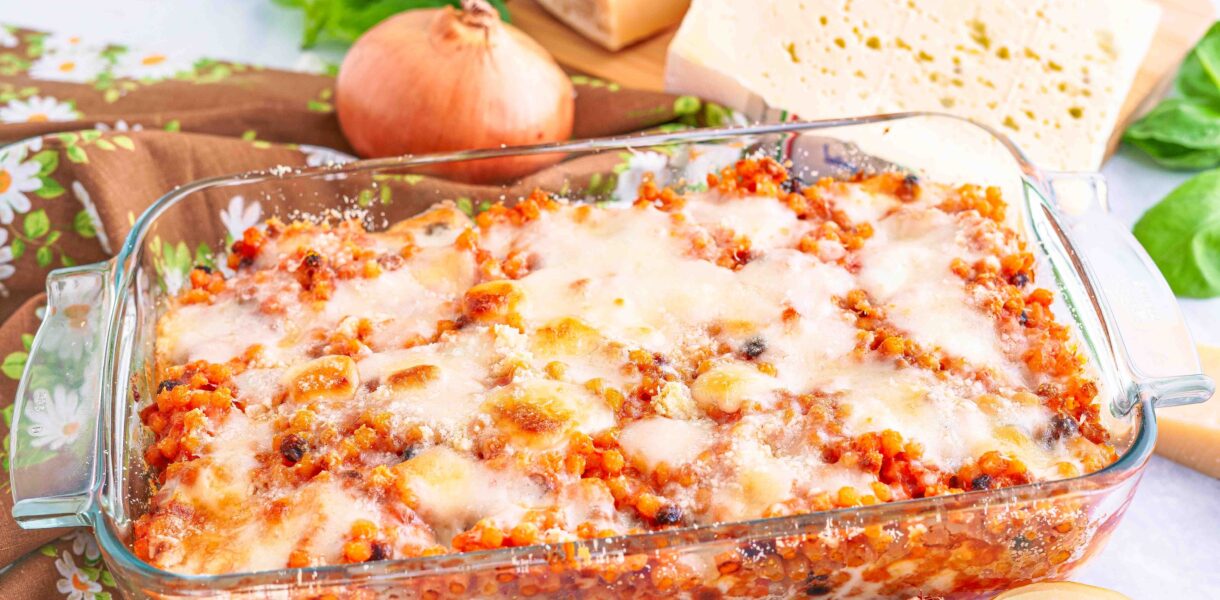 Teglia di fregola tipica sarda con formaggi sul tagliere basilico e cipolla