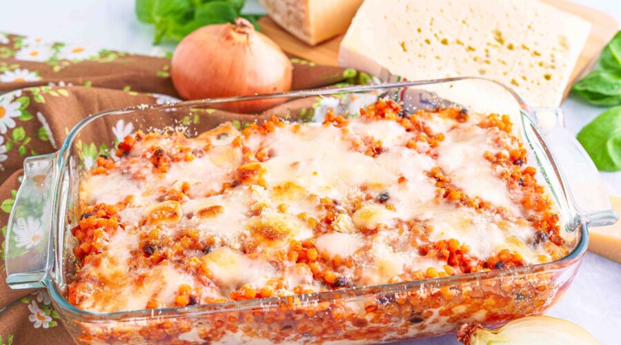Teglia di fregola tipica sarda con formaggi sul tagliere basilico e cipolla