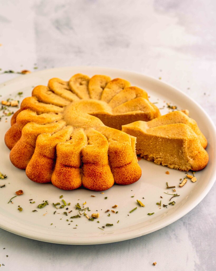 torta sul piatto bianco e sul tavolo con mix di erbe della tisana