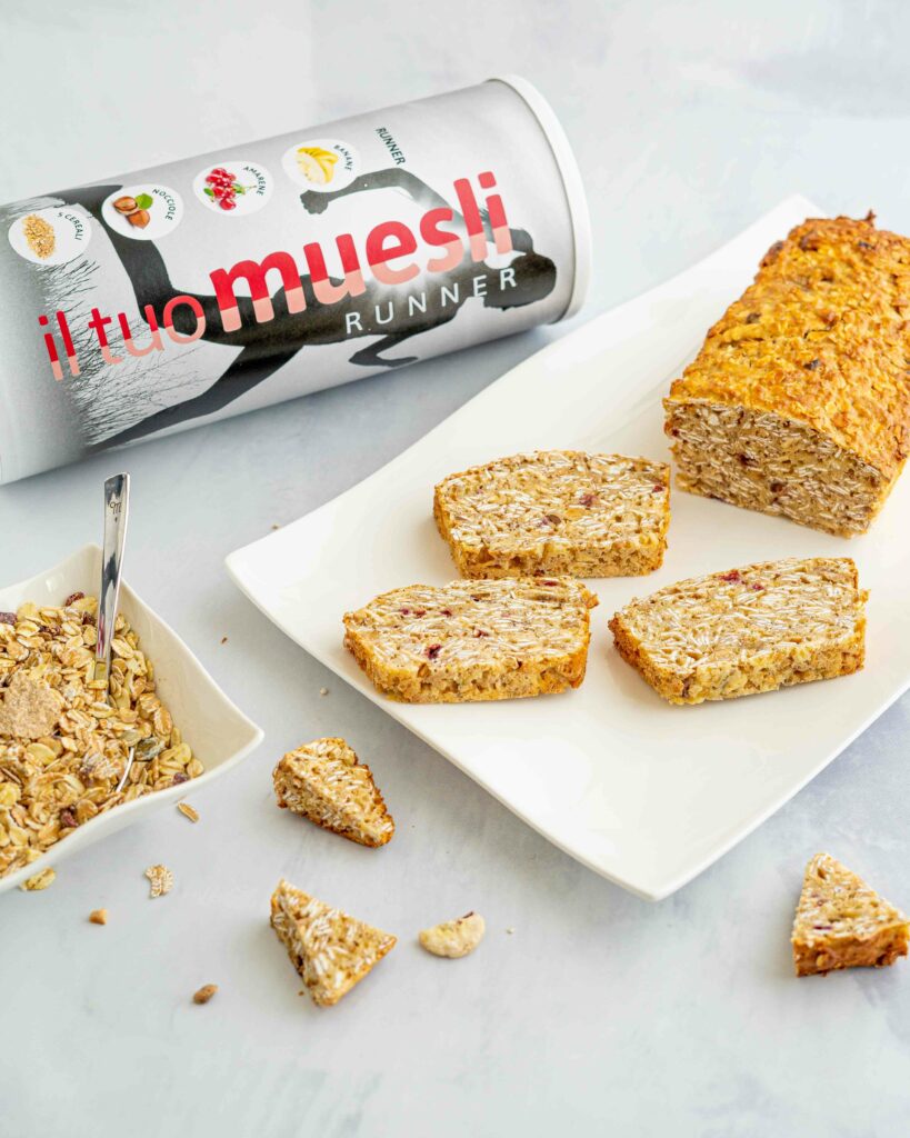 plumcake su piatto rettangolare bianco, ciotola con muesli e tubo della confezione di muesli