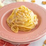 spaghetti sul piatto fondo rosa, nel tavolo cavolfiore aperto e noci