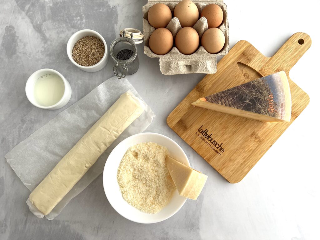 sul tavolo confezione di uova con ciotola di formaggio semi di sesamo e papavero, pasa sfoglia tagliere con formaggio