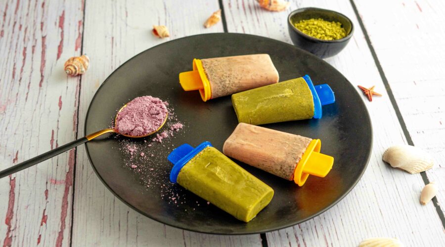 piatto nero con 4 ghiaccioli cucchiaio con taro, sul tavolo conchiglie e ciotola con matcha