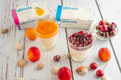 bicchiere con budino due confezioni di yogurt sul tavolo albicocche e ciliegie in ciotola