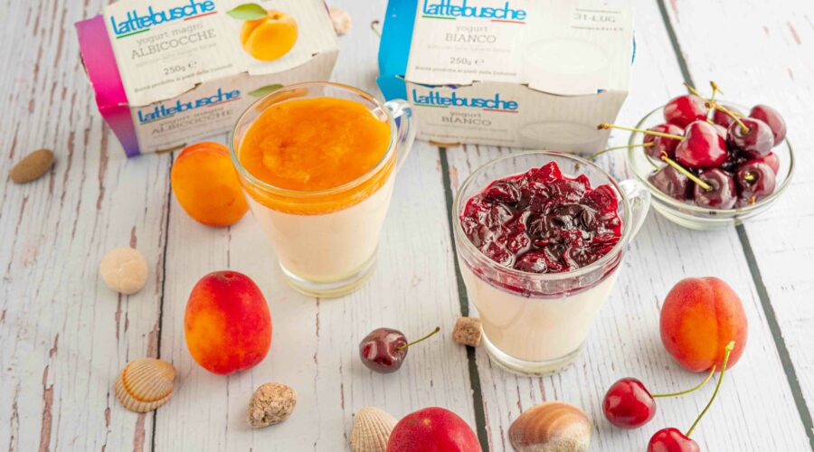 bicchiere con budino due confezioni di yogurt sul tavolo albicocche e ciliegie in ciotola