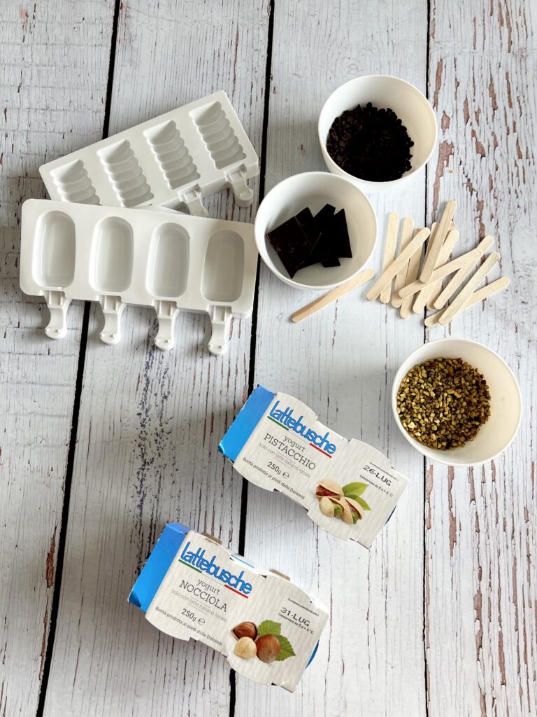 ingredienti sul tavolo stecchette confezioni di yogurt cioccolato nella ciotola, granella in ciotola e contenitori gelati