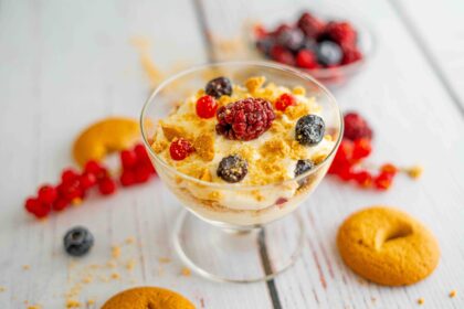 coppa con biscotti e mascarpone e frutti di bosco, sul tavolo frutti di bosco e biscotti