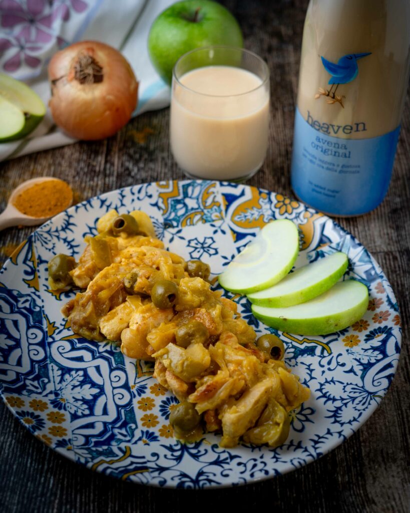 foto piatto con pollo e fette di mela sul piatto. cucchiaio con curry e bicchiere di latte con cipolla sul tavolo e la bottiglia del latte in plastica