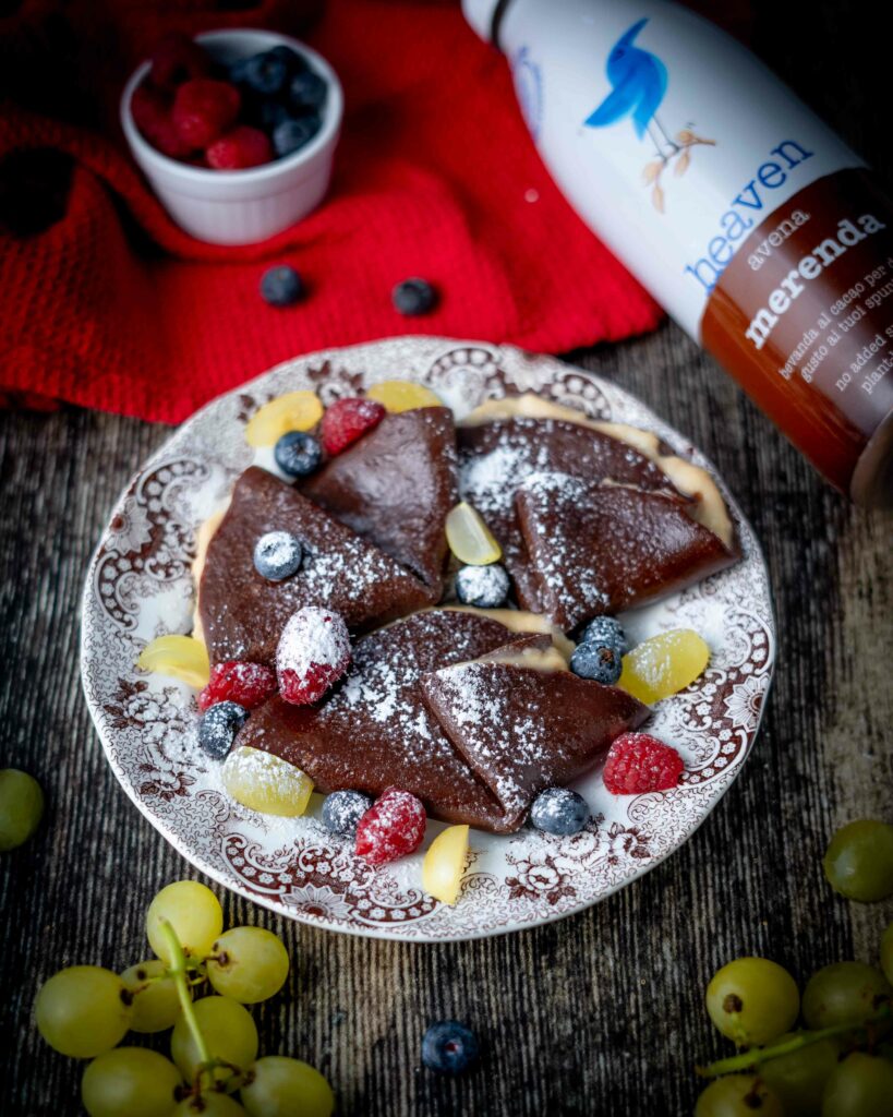 cepes al cioccolato con crutta fresca e crema
sul tavolo bottiglia di latte e uva e frutti rossi in ciottola sullo strofinaccio.