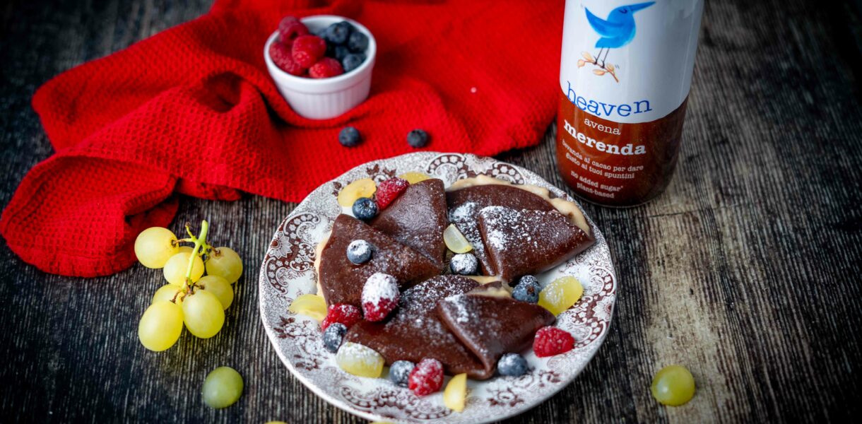 crepe sul piatto piccolo al cioccolato sul tavolo botiia di latte al cioccolato uva strofinaccio e frutti rossi