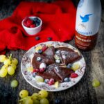 crepe sul piatto piccolo al cioccolato sul tavolo botiia di latte al cioccolato uva strofinaccio e frutti rossi