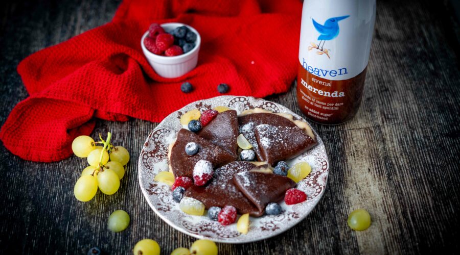 crepe sul piatto piccolo al cioccolato sul tavolo botiia di latte al cioccolato uva strofinaccio e frutti rossi