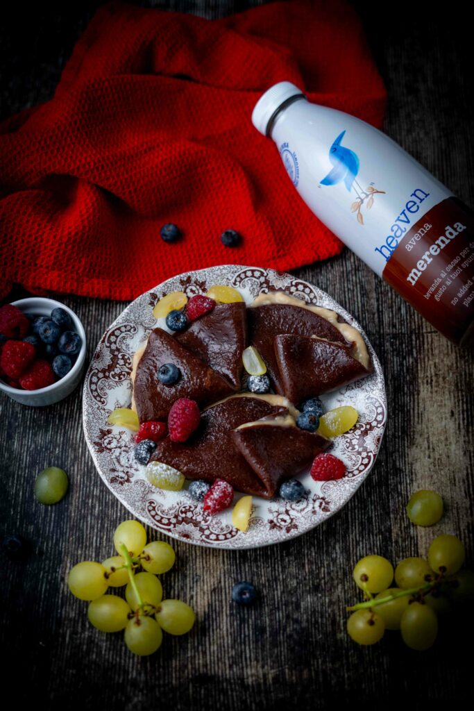 foto cepes al cioccolato con crutta fresca e crema
sul tavolo bottiglia di latte e uva e frutti rossi in ciottola sullo strofinaccio.
