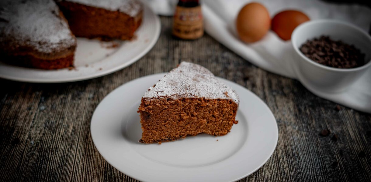 torta al cioccolato con fetta sul piatto bianco sul tavolo gocce di cioccolato e uova