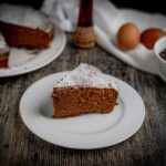 torta al cioccolato con fetta sul piatto bianco sul tavolo gocce di cioccolato e uova