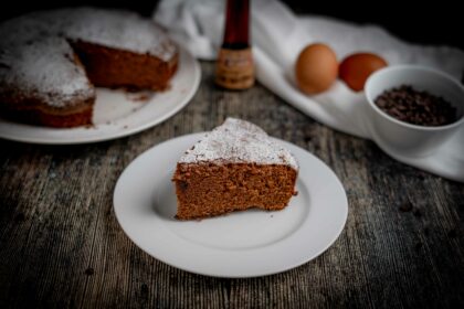 torta al cioccolato con fetta sul piatto bianco sul tavolo gocce di cioccolato e uova