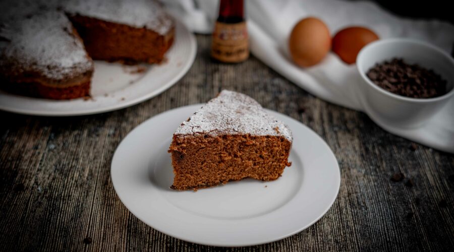 torta al cioccolato con fetta sul piatto bianco sul tavolo gocce di cioccolato e uova