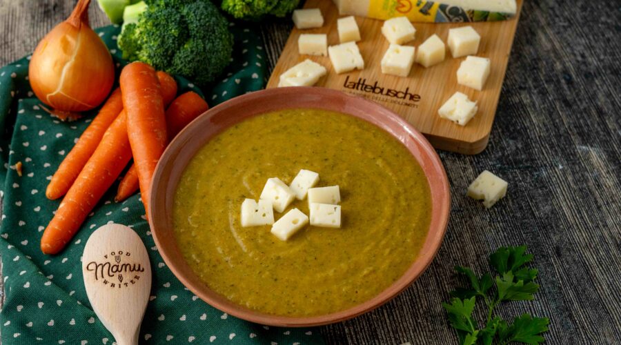 VELLUTATA DIVERDE SUL PIATTO CAROTE SU TAVOLO CON BROCCOLO CRUDO E CIPOLLA TAGLIERE CON FORMAGGIO