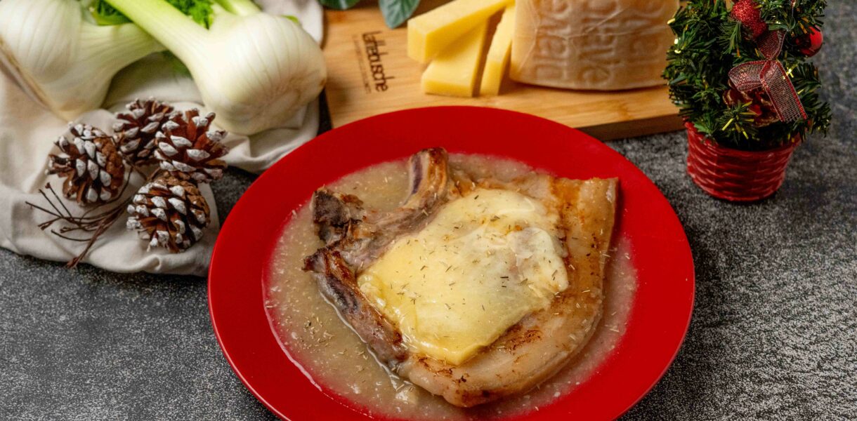 brciola di maiale con formaggio sciolto nel piatto rosso sul tavolo addobbi natalizi e pezzo di formaggio