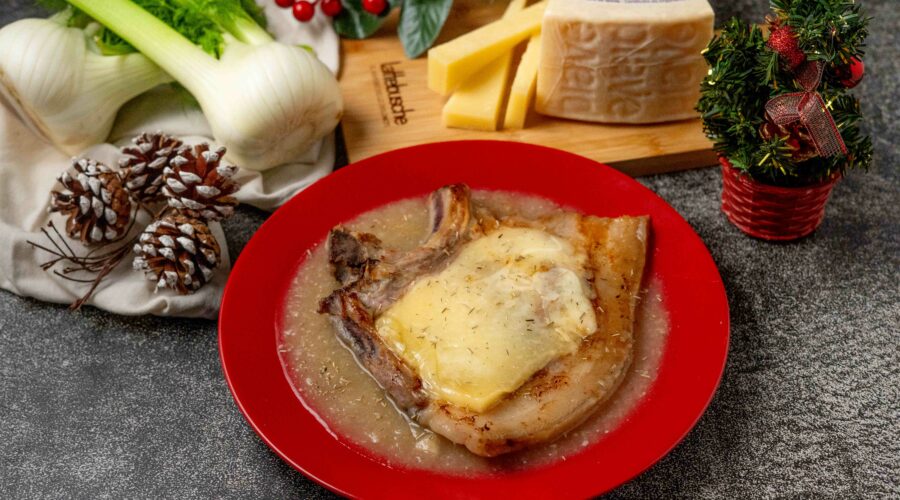 brciola di maiale con formaggio sciolto nel piatto rosso sul tavolo addobbi natalizi e pezzo di formaggio