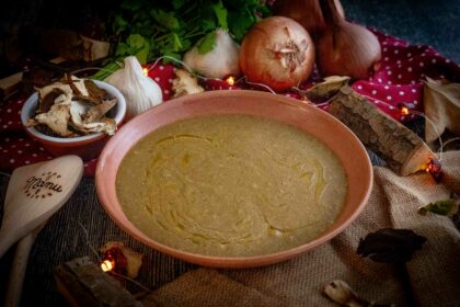 crema ai funghi nel piatto con cipolla e fughi sul tavolo