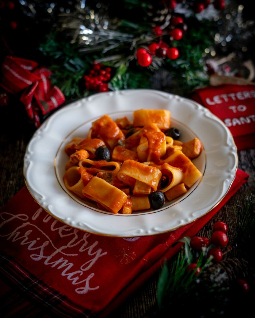 piatto di pasta con pesce spada sullo strofinaccio natalizio con decorazioni sul tavolo di natale 