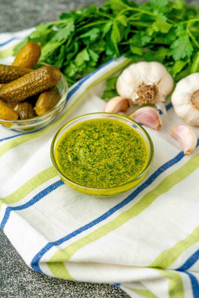ciottola con salsa verde e ciottola con cetrioli prezzemolo mazzo e teste di aglio nello strofinaccio