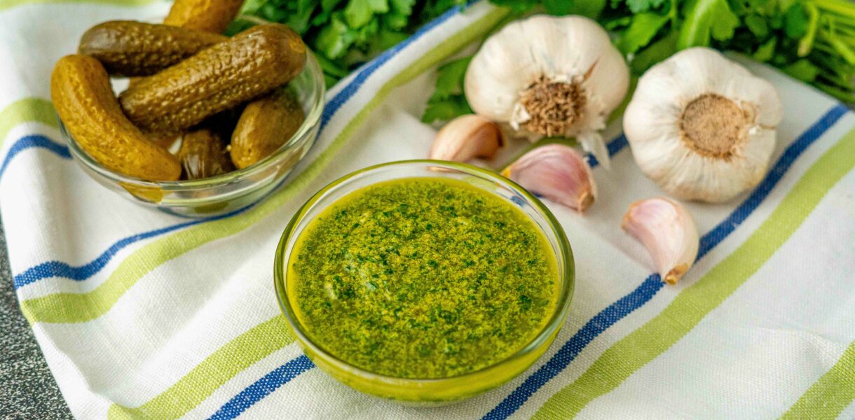 ciotola con salsa verde con ciotola di cetrioli sul tavolo stroniaccio e teste di aglio e prezzemolo