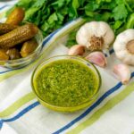 ciotola con salsa verde con ciotola di cetrioli sul tavolo stroniaccio e teste di aglio e prezzemolo