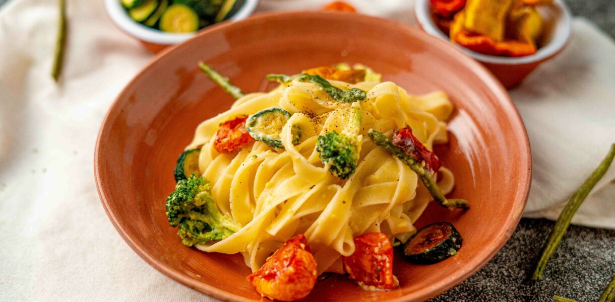 piatto di pasta con verdure disidratate in ciottola vicino sulos trofinaccio panna sul tavolo