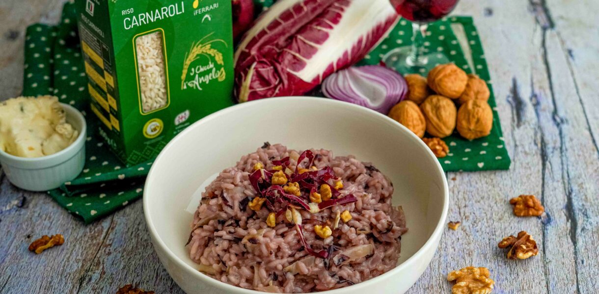 riso nel piatto con scatola di riso e bicchiere di vino rosso e noci e radicchio sul tavolo