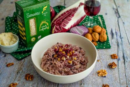 riso nel piatto con scatola di riso e bicchiere di vino rosso e noci e radicchio sul tavolo