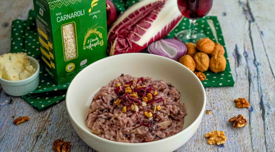 riso nel piatto con scatola di riso e bicchiere di vino rosso e noci e radicchio sul tavolo